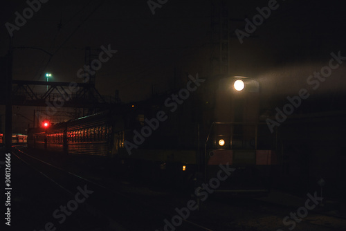 passenger train in mystical night illumination follows in a little fog