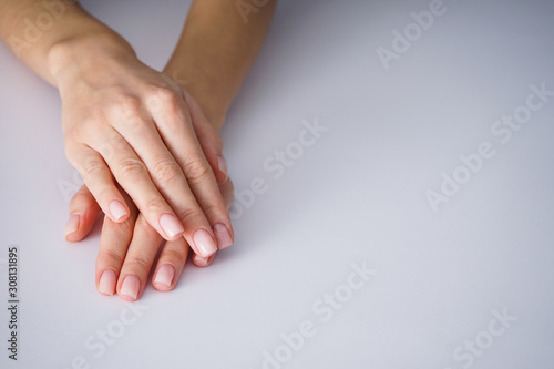 Female hands with a nice manicure on gray background place for text.