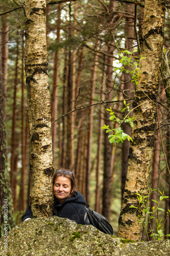 Tourist young woman hugging a tree in the forest during the mountain hike.Connecting to nature, protect the environment concept