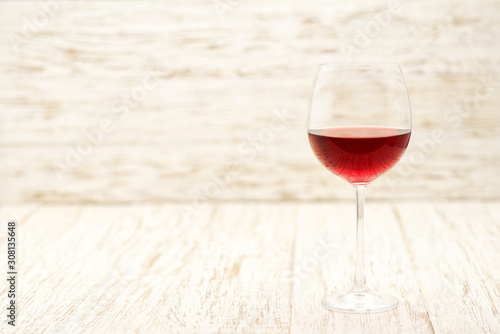 Full glass of red wine on a white wooden background, with copy space.