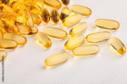 group of yellow fish oil capsules on a white table