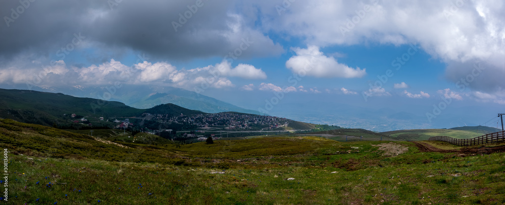 Panorama view of colorful mountains, meadow, and valley with clouds in the background.Ski resort. Early morning, Sharr Mountains, Popova Shapka, North Macedonia.