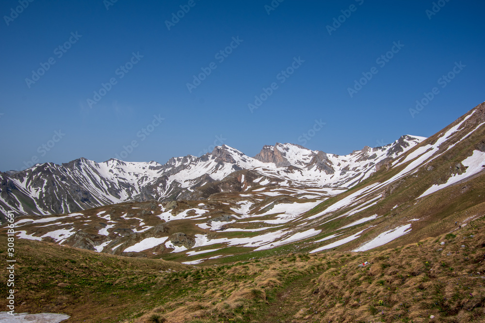 Landscape view of snow-capped mountains, meadow, and valley. SpringTime in Mavrovo national park, North Macedonia.