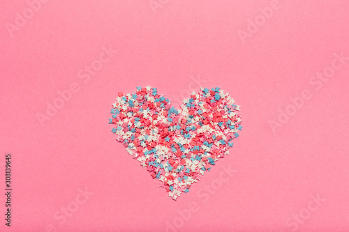 Colorful small candies on the pink background.