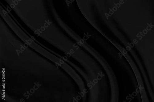 Black gray satin dark fabric texture luxurious shiny that is abstract silk cloth background with patterns soft waves blur beautiful.