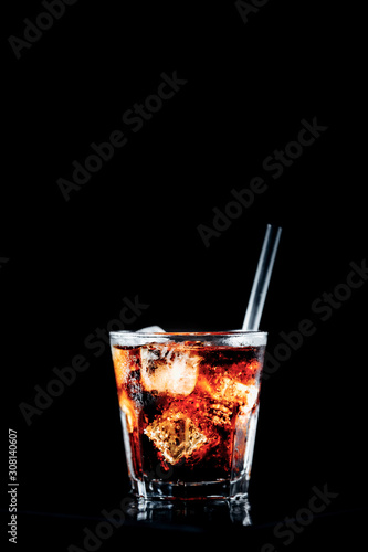 Cuba libre cocktail at the bar stand. Black background with place for text. Vertical