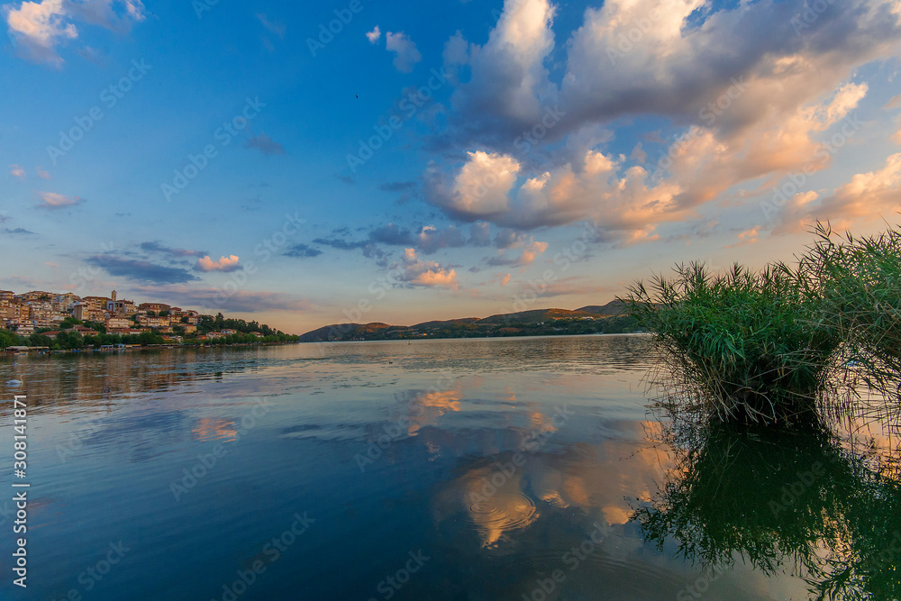 Sunset view of a calm lake reflecting the blue and pink colours of the sky and clouds. The city of Kastoria, northern Greece visible in the background.