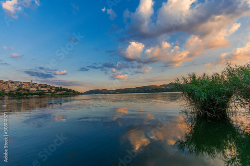 Sunset view of a calm lake reflecting the blue and pink colours of the sky and clouds. The city of Kastoria, northern Greece visible in the background. © Kostas