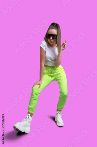 Girl in a white T-shirt and yellow neon sweatpants on a colored background