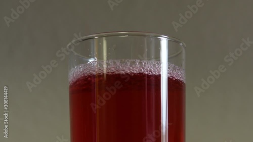 Video close up of the top of a clear glass being filled with cranberry juice. Bubbles forming in the glass. Fresh natural juice. 4K video.  Real time. No people.