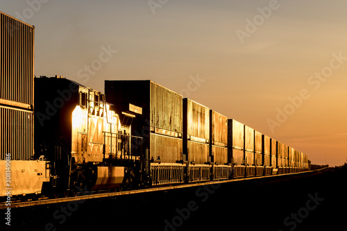 Locomotive and Train Carrying Shipping Containers in Golden Sunset on the Canadian Prairie