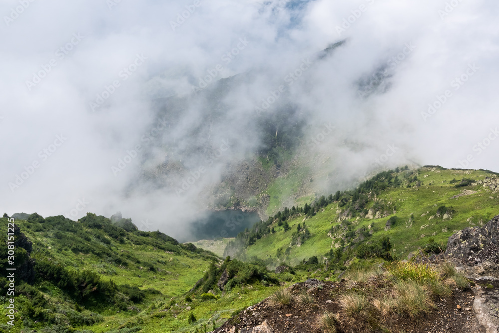View of a mountain lake from the top of the mountain through the fog View of a mountain lake from the top of the mountain through the fog