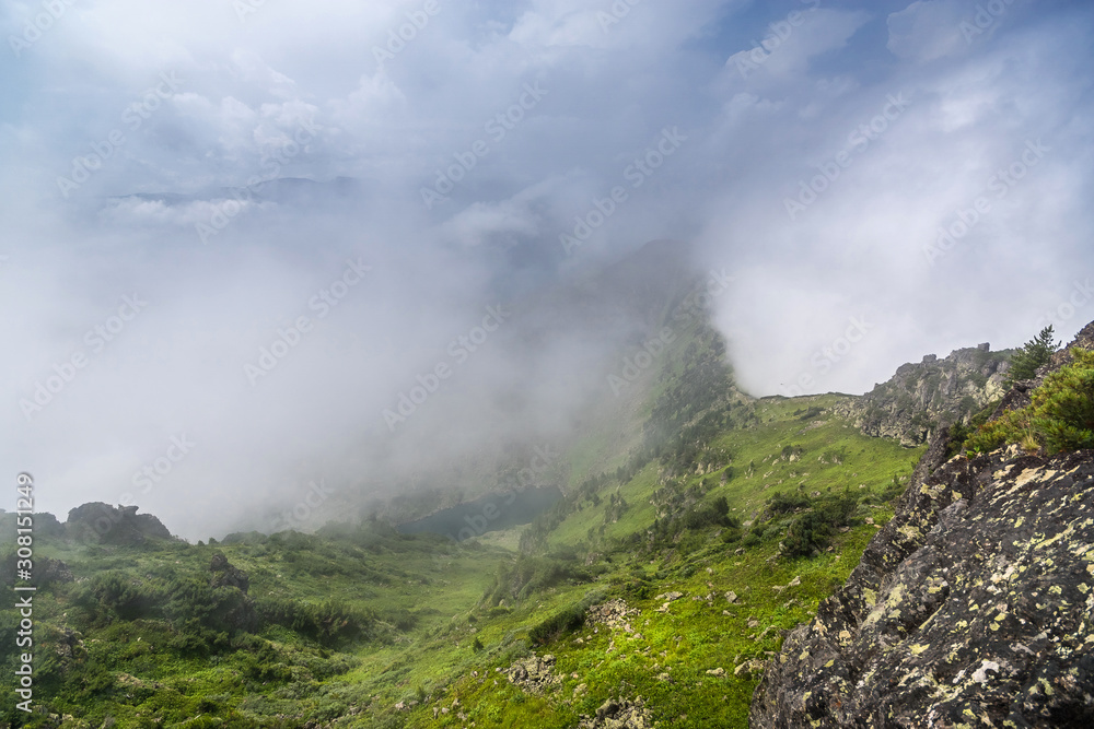 View of a mountain lake from the top of the mountain through the fog View of a mountain lake from the top of the mountain through the fog
