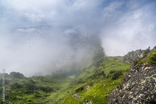 View of a mountain lake from the top of the mountain through the fog