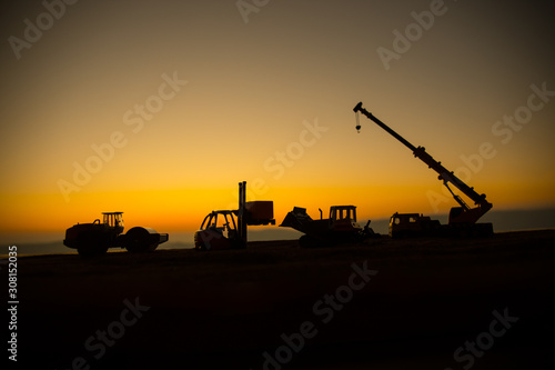Abstract Industrial background with construction crane silhouette over amazing sunset sky. Mobile crane against the evening sky. Industrial skyline. Selective focus
