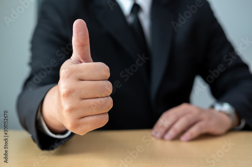 Business men wear suits sitting at desks and showing thumbs up