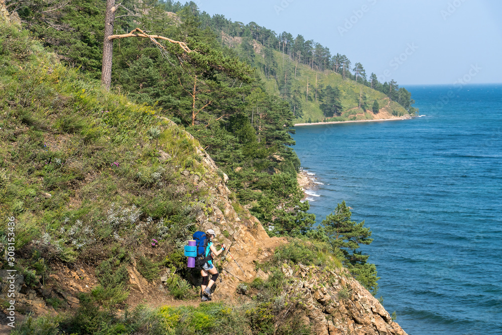 Girl tourist goes on a rocky trail over Lake Baikal