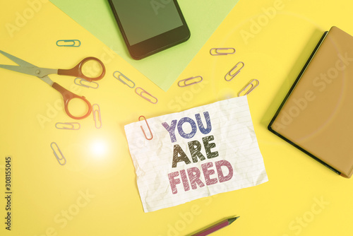Text sign showing You Are Fired. Business photo text Getting out from the job and become jobless not end the career Paper sheets pencil clips smartphone scissors notebook colored background photo