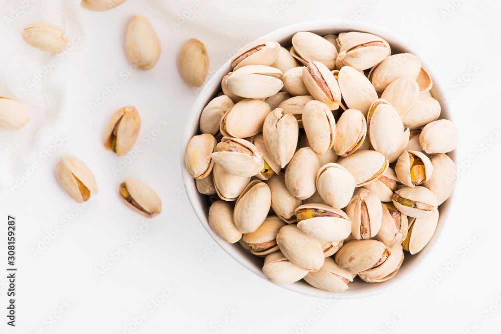 Bowl of roasted pistachios on a white background Bowl of roasted pistachios on a white background