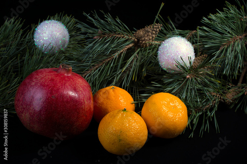 fruits tangerines lemon pomegranate on a dark background with Christmas tree