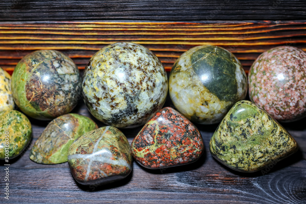 Collection of processed stones of different colors - magmatites - on a wooden background Collection of processed stones of different colors - magmatites - on a wooden background