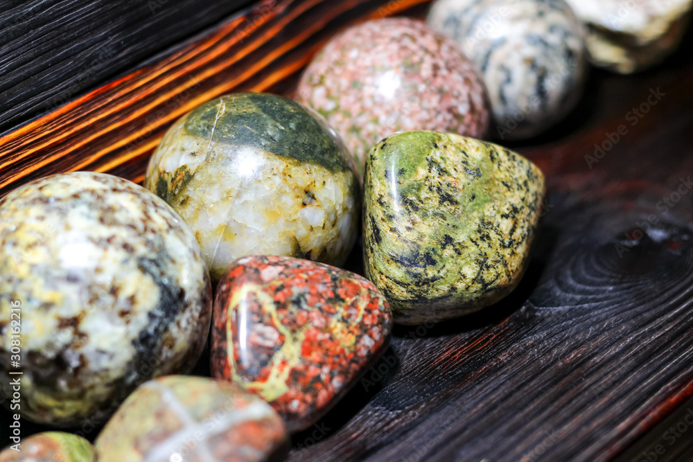 Collection of processed stones of different colors - magmatites - on a wooden background Collection of processed stones of different colors - magmatites - on a wooden background