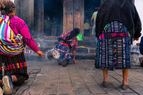 Tres mujeres mayas están echando  incienso en la entrada de la Iglesia de Santo Tomas Chichicastenango Guatemala. photo