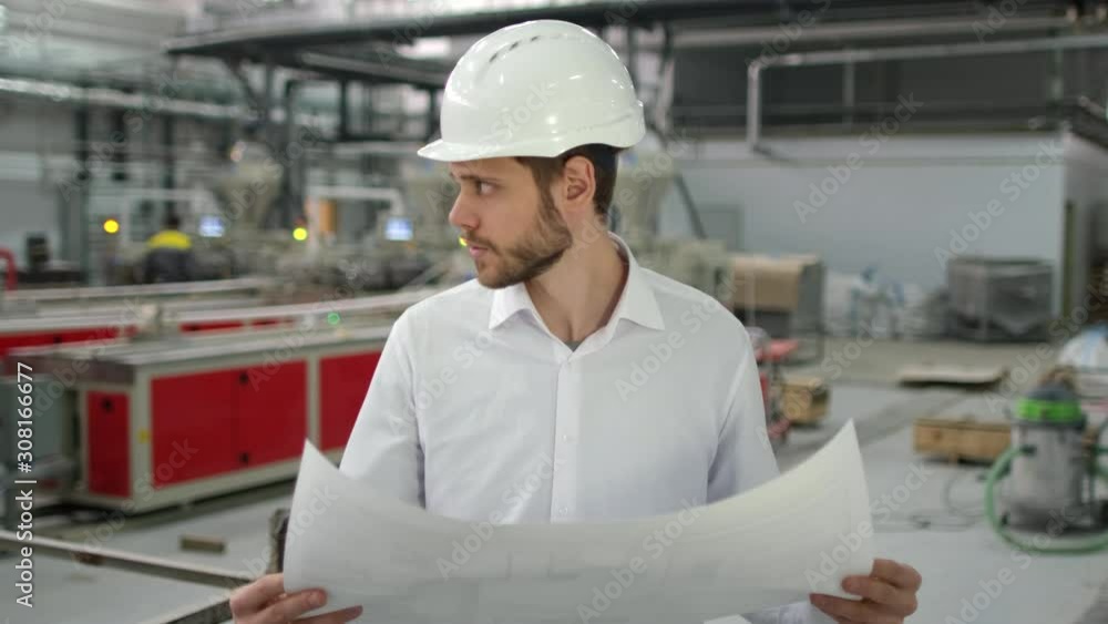 caucasian young bearded professional male architect engineer man people in hard hat with drawing design working on engineering background on manufacture plant indoors, worker inspection, slow-mo 4 K caucasian young bearded professional male architect engineer man people in hard hat with drawing design working on engineering background on manufacture plant indoors, worker inspection, slow-mo 4 K