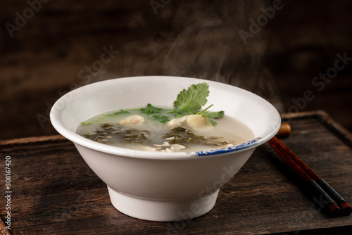 Shrimp wonton with braised pork in soup on wooden table / Select focus image...