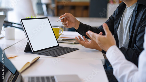 Fotografie Mockup blank white desktop screen tablet with a man and woman are working in background