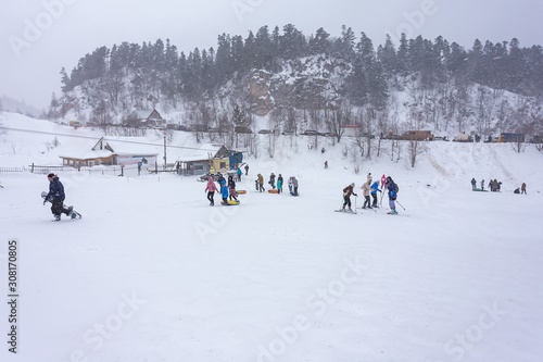 Winter holidays in the mountains, different sports, family entertainment, snowy and cloudy weather, soft focus, a place for text.