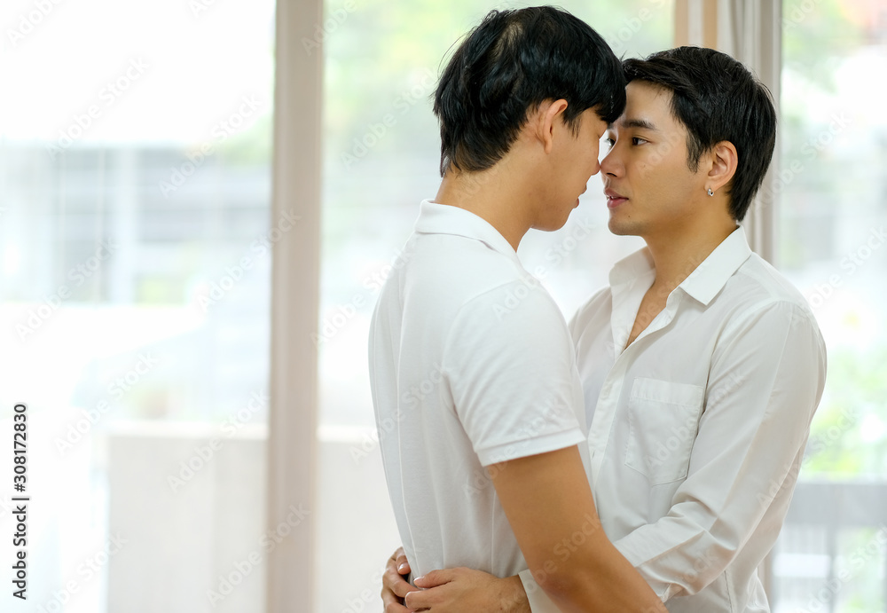Asian gay couple with white shirt touch their nose together in bed room with day light. Asian gay couple with white shirt touch their nose together in bed room with day light.
