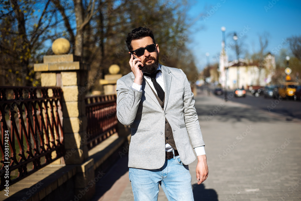 Young successful handsome man in a gray jacket is standing on the street Young successful handsome man in a gray jacket is standing on the street