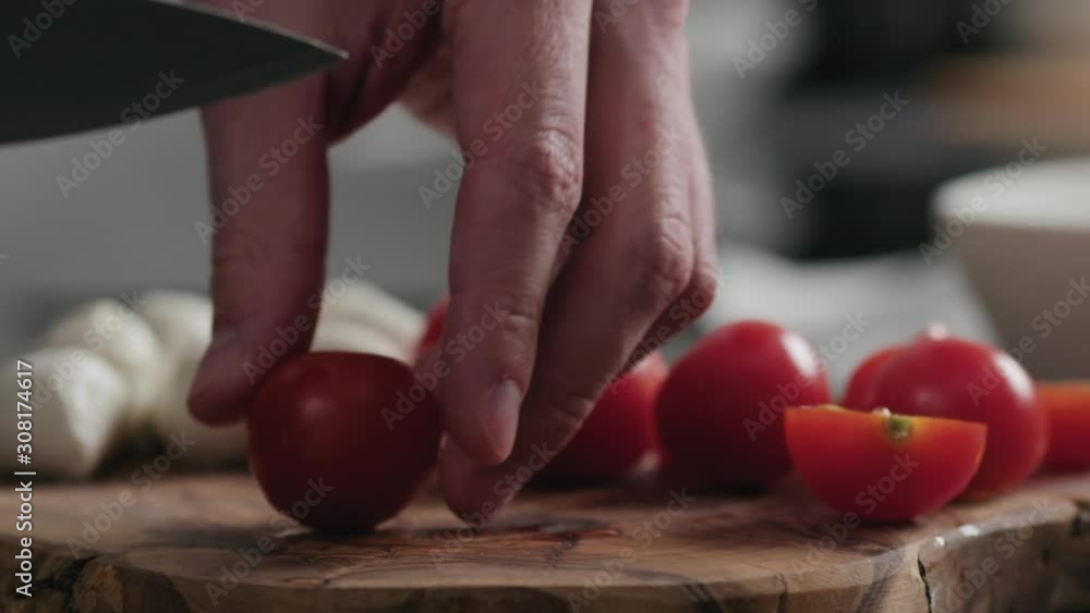 Slow motion closeup man cutting cherry tomatoes on oak board Slow motion closeup man cutting cherry tomatoes on oak board