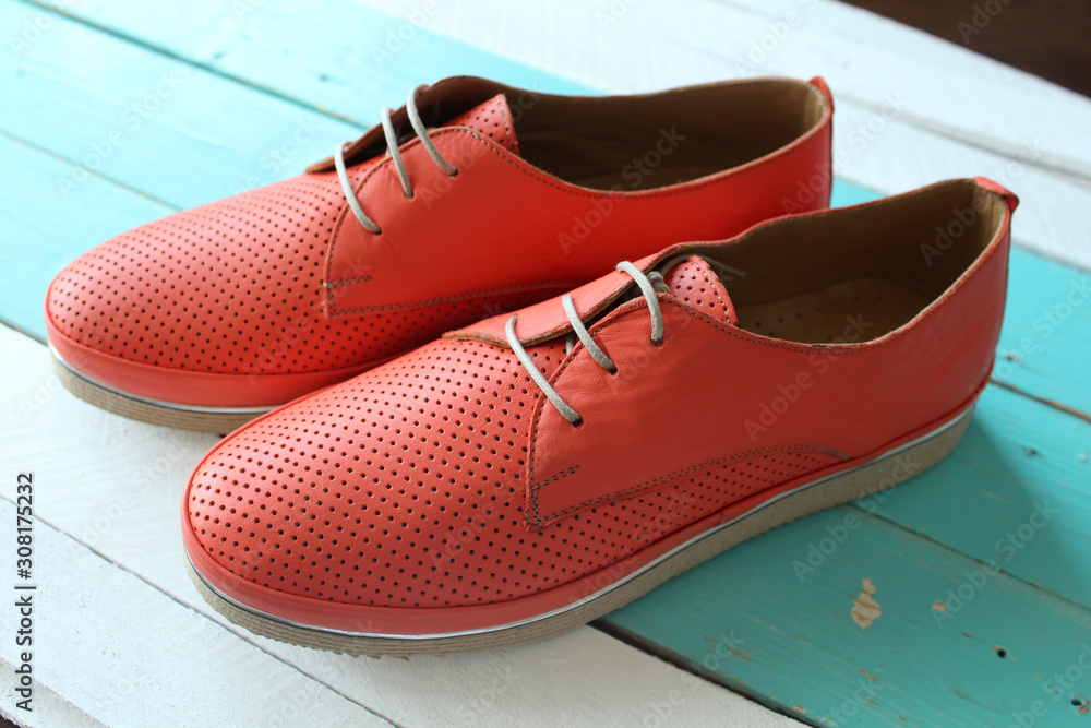 Naklejka premium fashionable leather orange flat shoes on a wooden stand