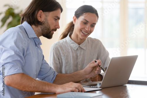 Male team leader showing new corporate computer software to intern.