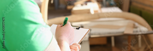 Arms of worker making notes on clipboard with green pen