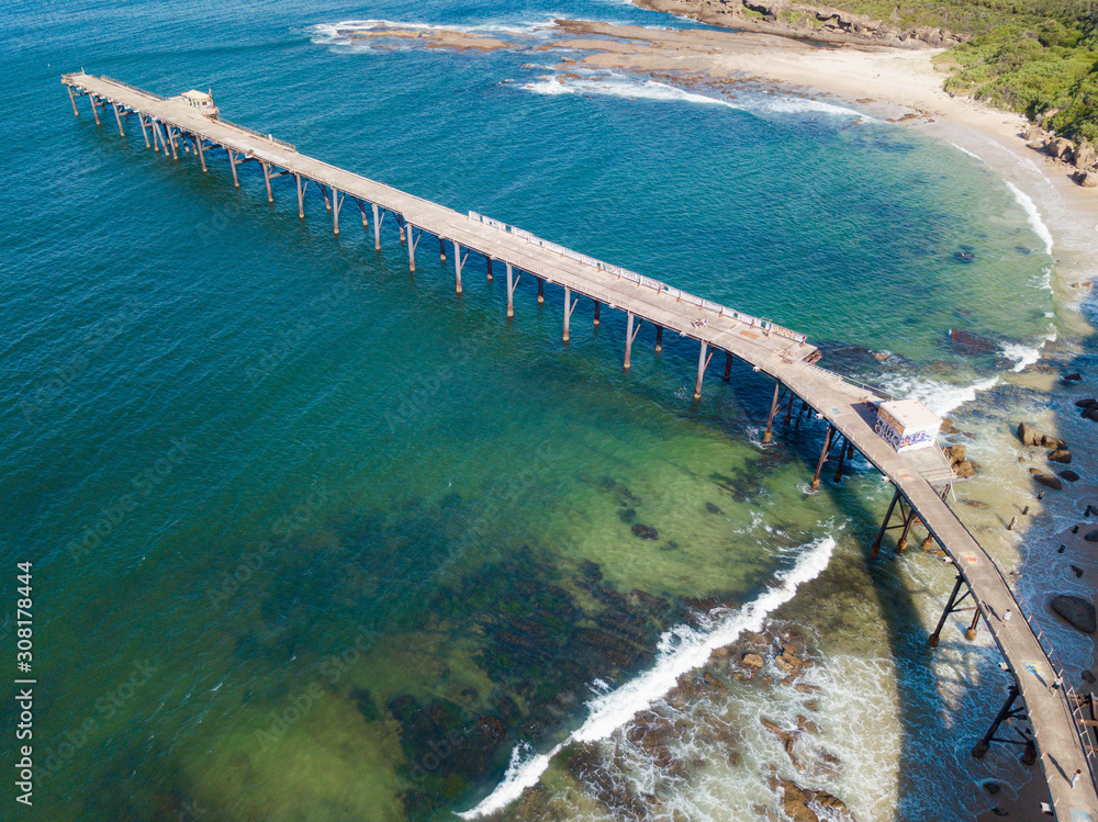 Aerial view of a jetty above turquoise water beach.