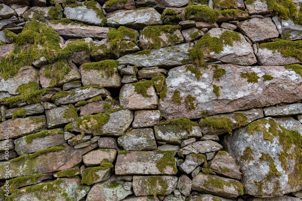 an old manmade stone wall with moss on it an old manmade stone wall with moss on it
