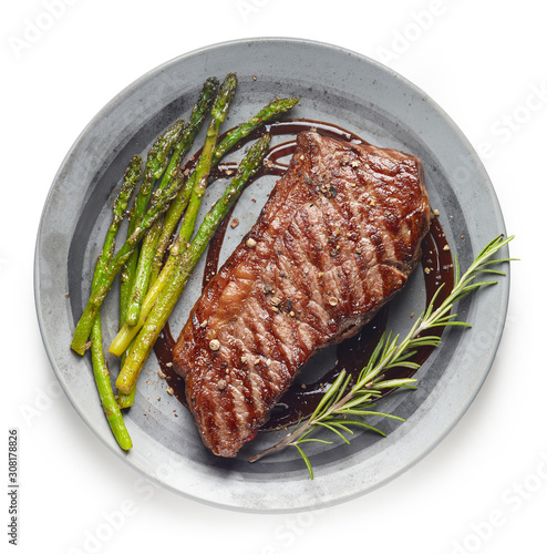 Cooked Beef steak on grey plate with asparagus and rosemary on white background