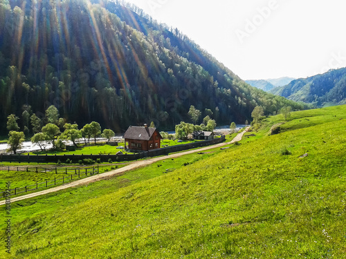 Fotografi A house by the river in a mountain valley consecrated by the sun.