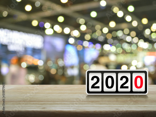 Retro flip clock with 2020 text on wooden table over blur light and shadow of shopping mall, Happy new year 2020 cover concept