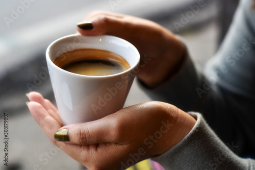 Warm black coffee in a white cup with a woman hand.