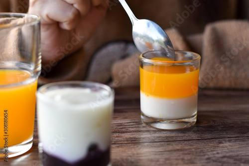 Orange flavored yogurt in glass shot on wooden table.