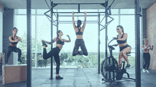 Group of strong active female athletes having training in modern gym,