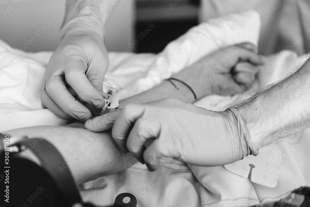 Krankenpfleger setzt Nadel für einen Zugang am Arm einer Patientin