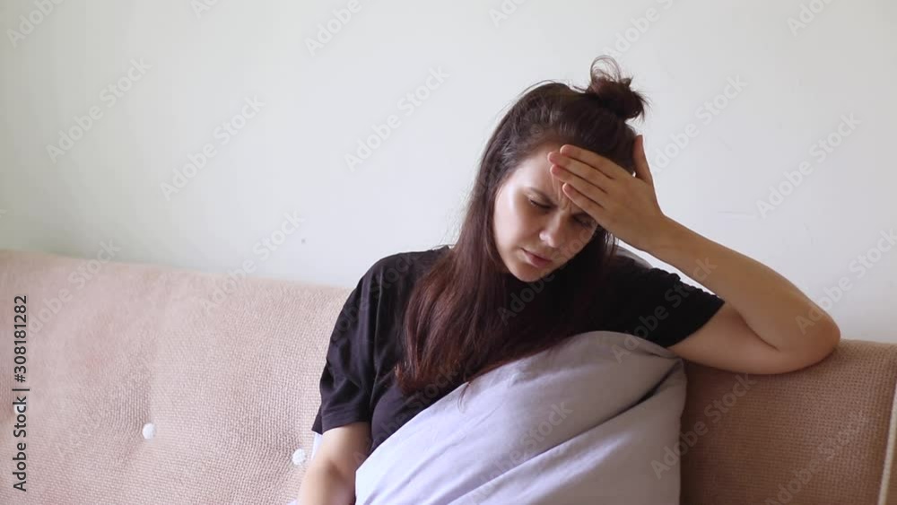 Sick young woman sitting at home with severe headache Sick young woman sitting at home with severe headache