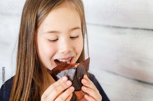 Portrait of a smiling girl with a beautiful cupcake in paper packaging