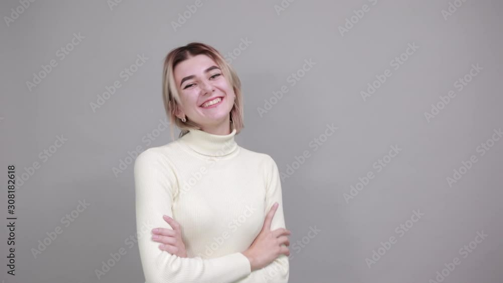 Happy young woman in casual clothes holding hands crossed, isolated on gray wall background. People sincere emotions, lifestyle concept. Happy young woman in casual clothes holding hands crossed, isolated on gray wall background. People sincere emotions, lifestyle concept.
