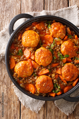 Delicious meatballs stewed with lentils and vegetables close-up in a pan. Vertical top view